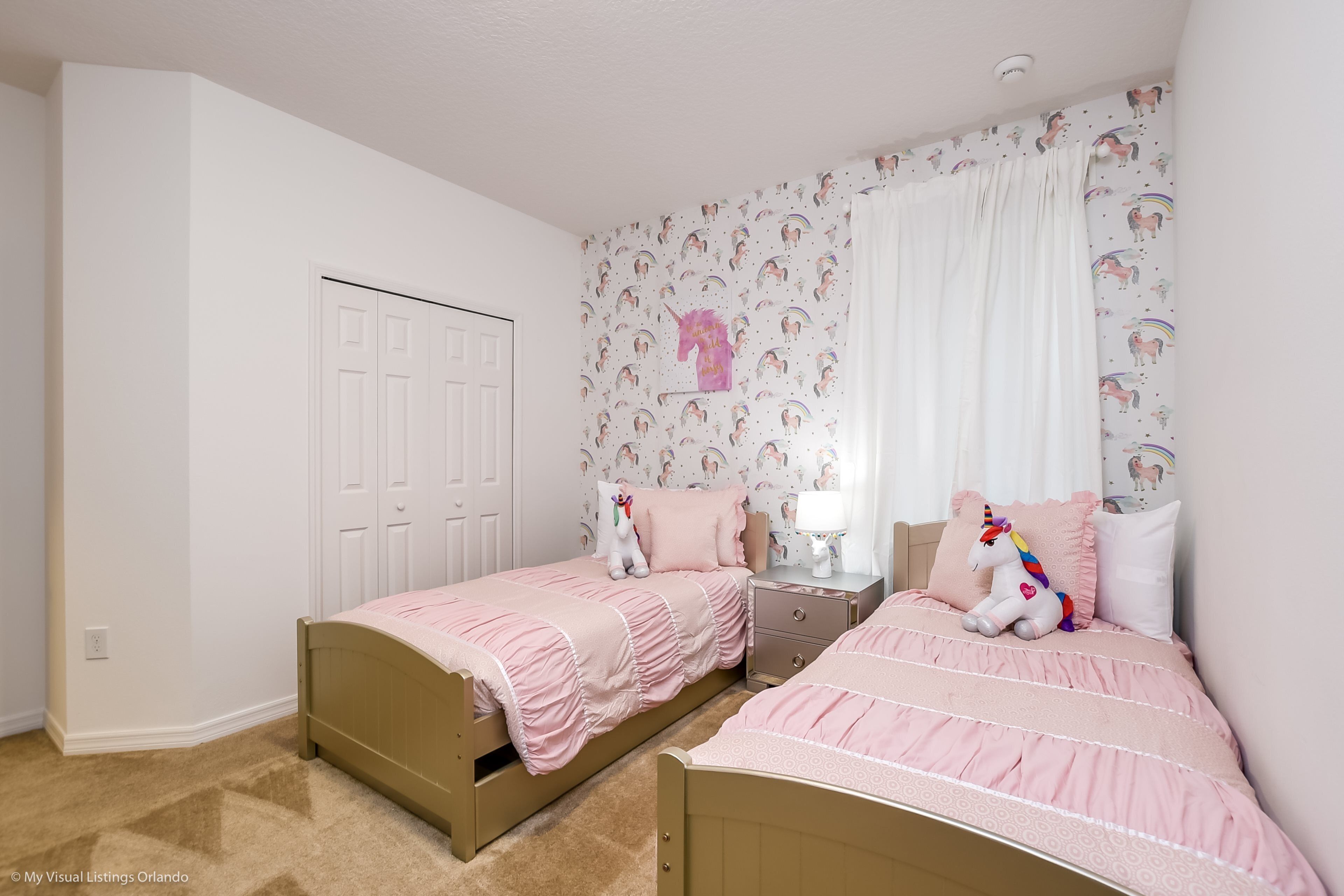 Een slaapkamer met twee eenpersoonsbedden, een nachtkastje, een dressoir en een deur.