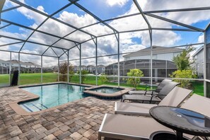 A covered outdoor swimming pool area with lounge chairs and a hot tub, surrounded by a metal frame structure. - 6 Bdrmgolf Coursegated Resort (Davenport)