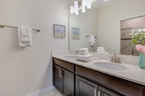 A modern bathroom with two sinks, dark cabinets, and a large mirror with lights. - 6 Bdrmgolf Coursegated Resort (Davenport)
