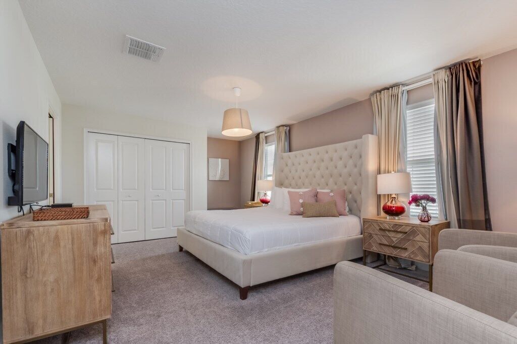 A hotel room with a large bed, a TV, a wooden side table, and a seating area.