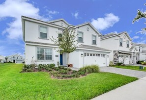 A two-story residential building with a garage, a well-maintained lawn, and a clear blue sky. - 6 Bdrmgolf Coursegated Resort (Davenport)