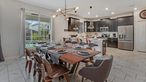 A modern kitchen with dark cabinets, stainless steel appliances, and a dining area with a wooden table and chairs. - 6 Bdrmgolf Coursegated Resort (Davenport)