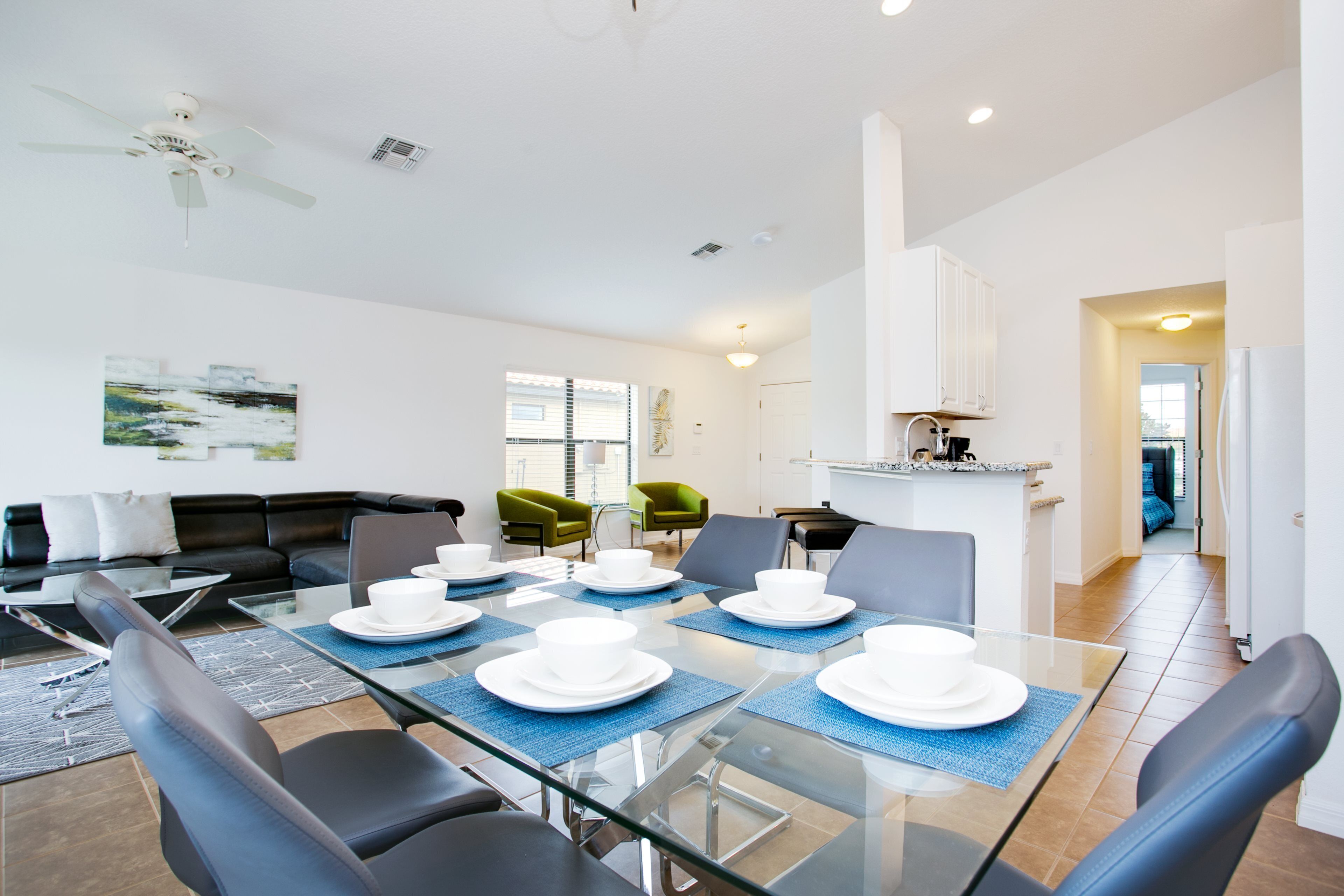 Un espace repas moderne avec une table en verre pouvant accueillir six personnes, entourée de chaises noires.