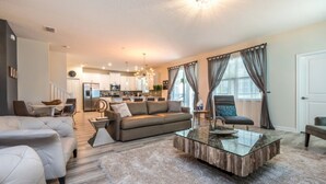 A modern living room with a glass coffee table, a sofa, and a dining area in the background. - 6 Bedroom 5 Bathroom Vacation Home (Davenport)