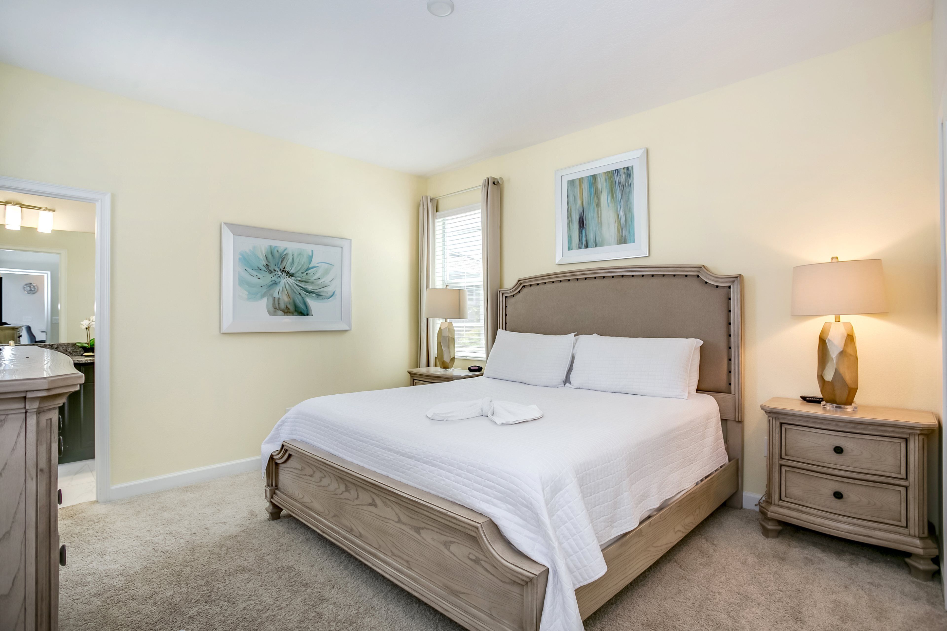 Une chambre bien rangée, avec un grand lit, des tables de chevet, une commode et un miroir.