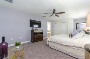 A bedroom with a bed, a dresser, a television, a ceiling fan, and a door leading to another room. - 6 Bedroom Champions Gate Villa (Davenport)