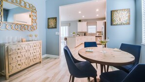 A dining area with a round table, blue chairs, and a decorative cabinet with geometric patterns.