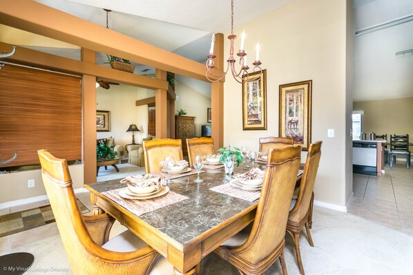 A dining room with a marble table, wooden chairs, and a chandelier.