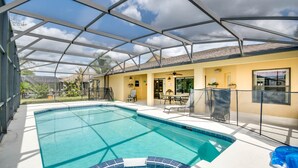 Una piscina interior con techo de vidrio, rodeada por un edificio amarillo con zona de patio y vistas al exterior.