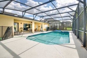 A covered outdoor swimming pool with a patio area, a yellow building, and a clear sky. - 908cov Spacious 5 Bedroom 3 Bathroom (Davenport)