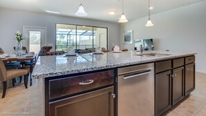 A spacious kitchen with granite countertops, stainless steel appliances, and pendant lighting. - 4bed 3Ba Home With Pool at Windsor (Kissimmee)