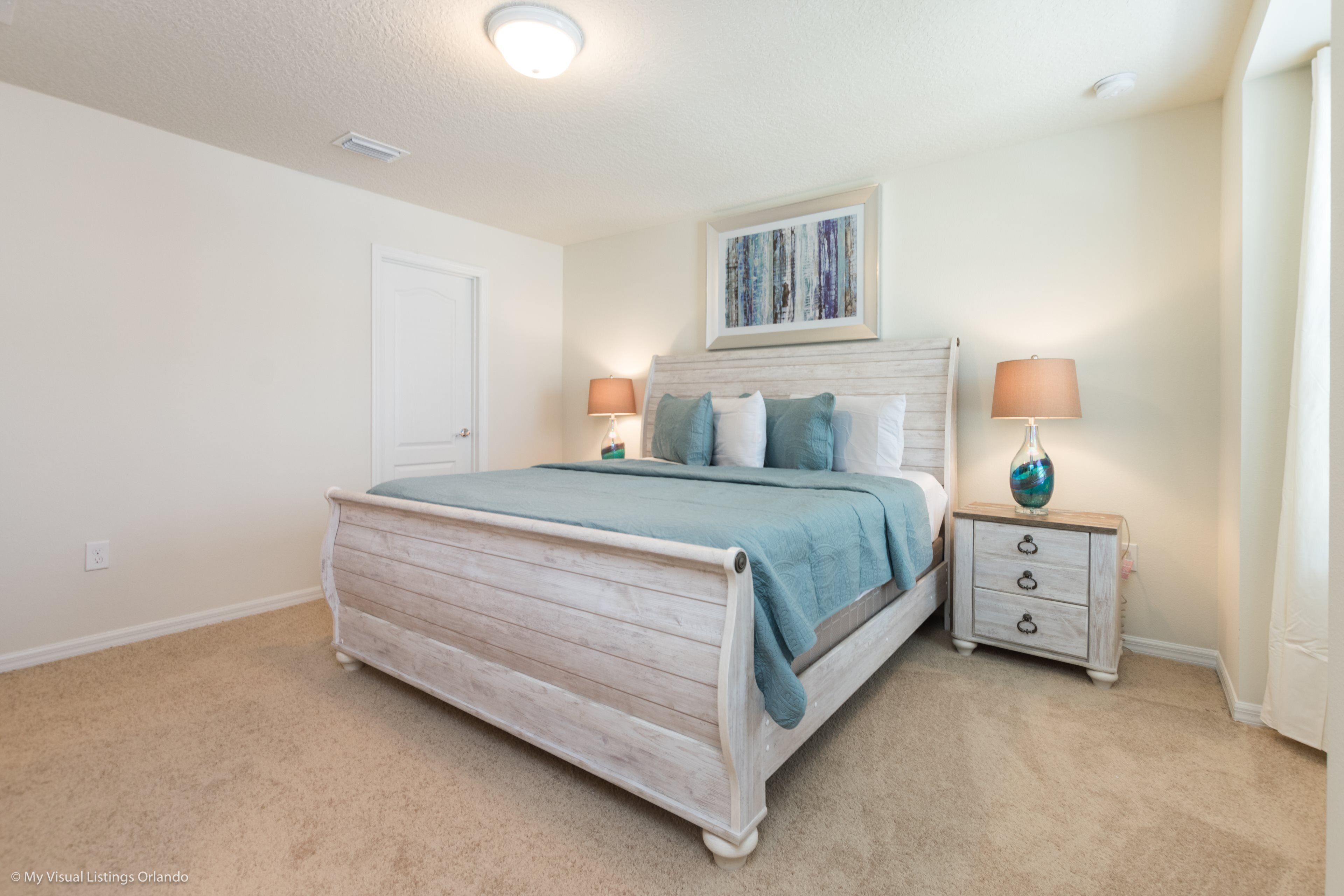 A bedroom with a bed, nightstands, a door, and a ceiling light.