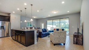 A spacious living area with a large island, dark wood cabinets, and a blue sofa. - 4bed 3Ba Home With Pool at Windsor (Kissimmee)
