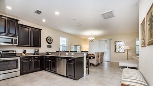 Una cocina amplia con muebles oscuros, una isla central y un comedor con banco.