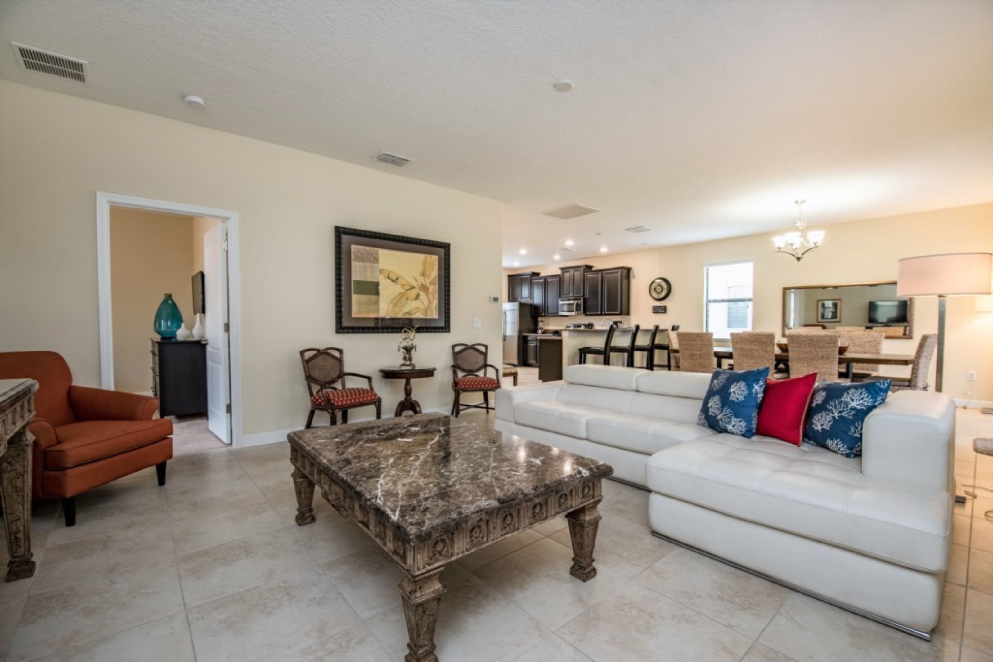 A spacious living room with a white sofa, a marble coffee table, and a dining area with wicker furniture.