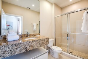 A modern bathroom with a granite countertop, a toilet, and a glass-enclosed shower. - Magic Village Resort 4 Bdrm Townhome (Kissimmee)