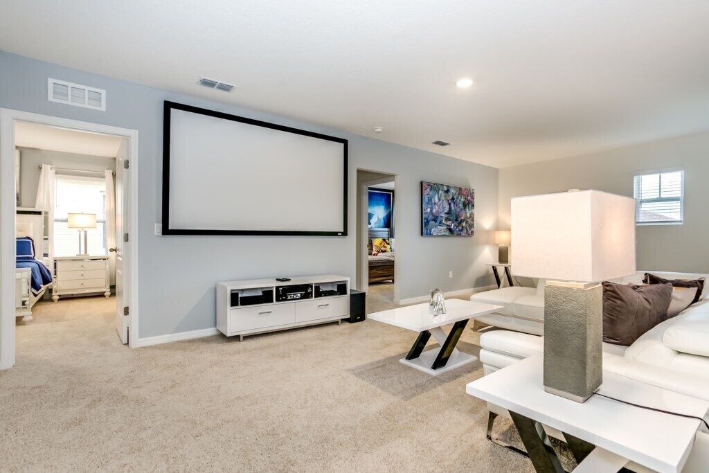 A modern living room with a flat-screen TV, a white sofa, a coffee table, and a TV stand with a speaker.