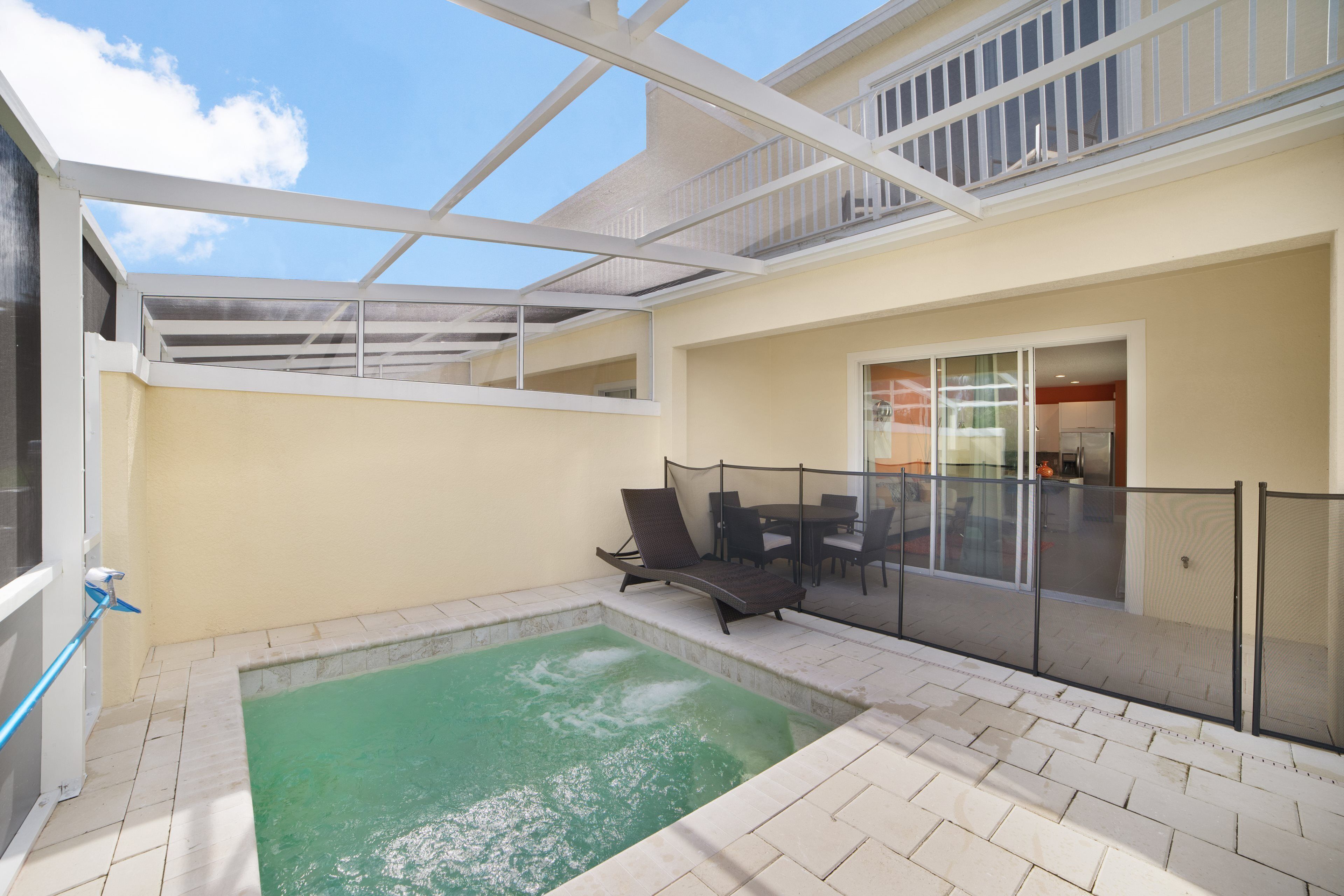 A covered outdoor area with a pool, seating, and a glass railing.