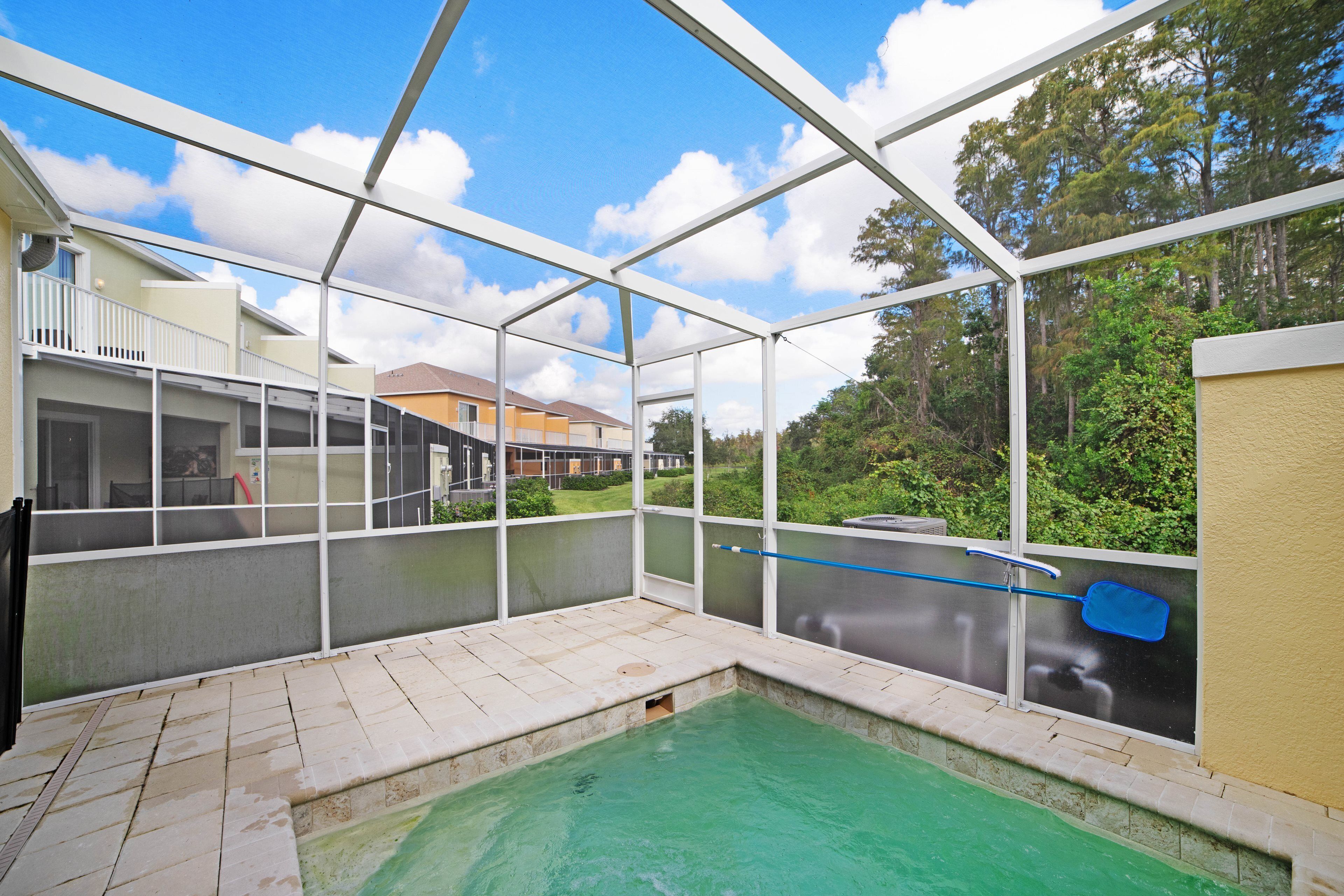 A covered outdoor swimming pool with a view of surrounding buildings and trees.