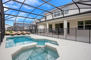 A modern indoor swimming pool with a glass ceiling, lounge chairs, and a clear view of the surrounding neighborhood. - 518mb New and Modern 8 Bedroom 5 Bathroom Villa (Kissimmee)