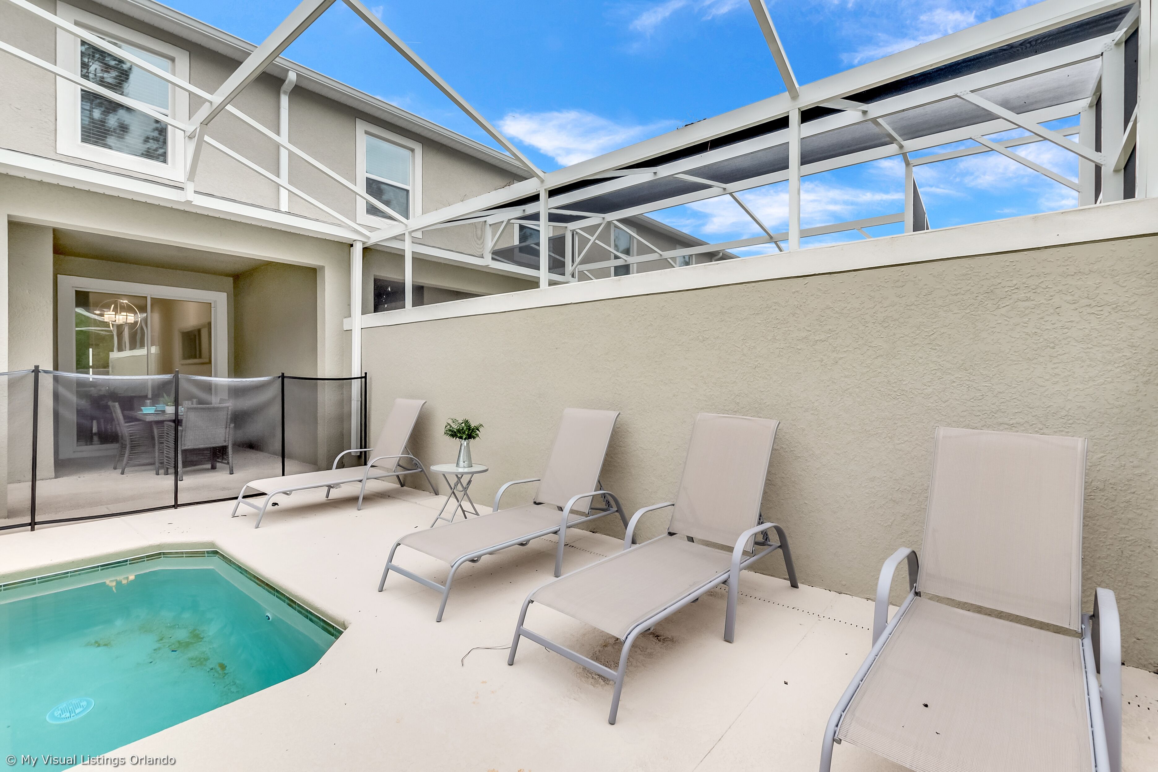 A poolside area with lounge chairs and a small table with a plant.