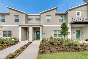 A modern two-story residential building with a stone facade, green doors, and a landscaped front yard. - Relaxing 4bed 3Ba Champions Gate Pool (Davenport)