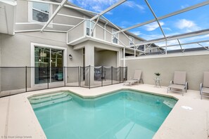 An indoor swimming pool with a glass enclosure, a covered patio area, and seating. - Relaxing 4bed 3Ba Champions Gate Pool (Davenport)