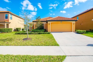 A residential area with a well-maintained lawn, a single tree, and a garage door.