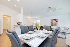 A modern dining area with a rectangular table set for six, surrounded by grey upholstered chairs.