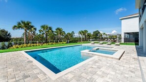 A rectangular swimming pool with a tiled deck, surrounded by palm trees and a clear blue sky. - Encore Resort Villa W Private Pool and Spa 7670 (Kissimmee)