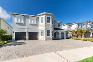 A two-story residential building with a stone facade, a garage, and a paved driveway.