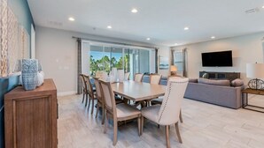 A spacious living area with a dining table and chairs, a sofa, and a flat-screen TV. - Encore Resort Villa W Private Pool and Spa 7670 (Kissimmee)