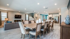 A modern living room with a dining area, a sofa, a TV, and a kitchen in the background. - Encore Resort Villa W Private Pool and Spa 7670 (Kissimmee)