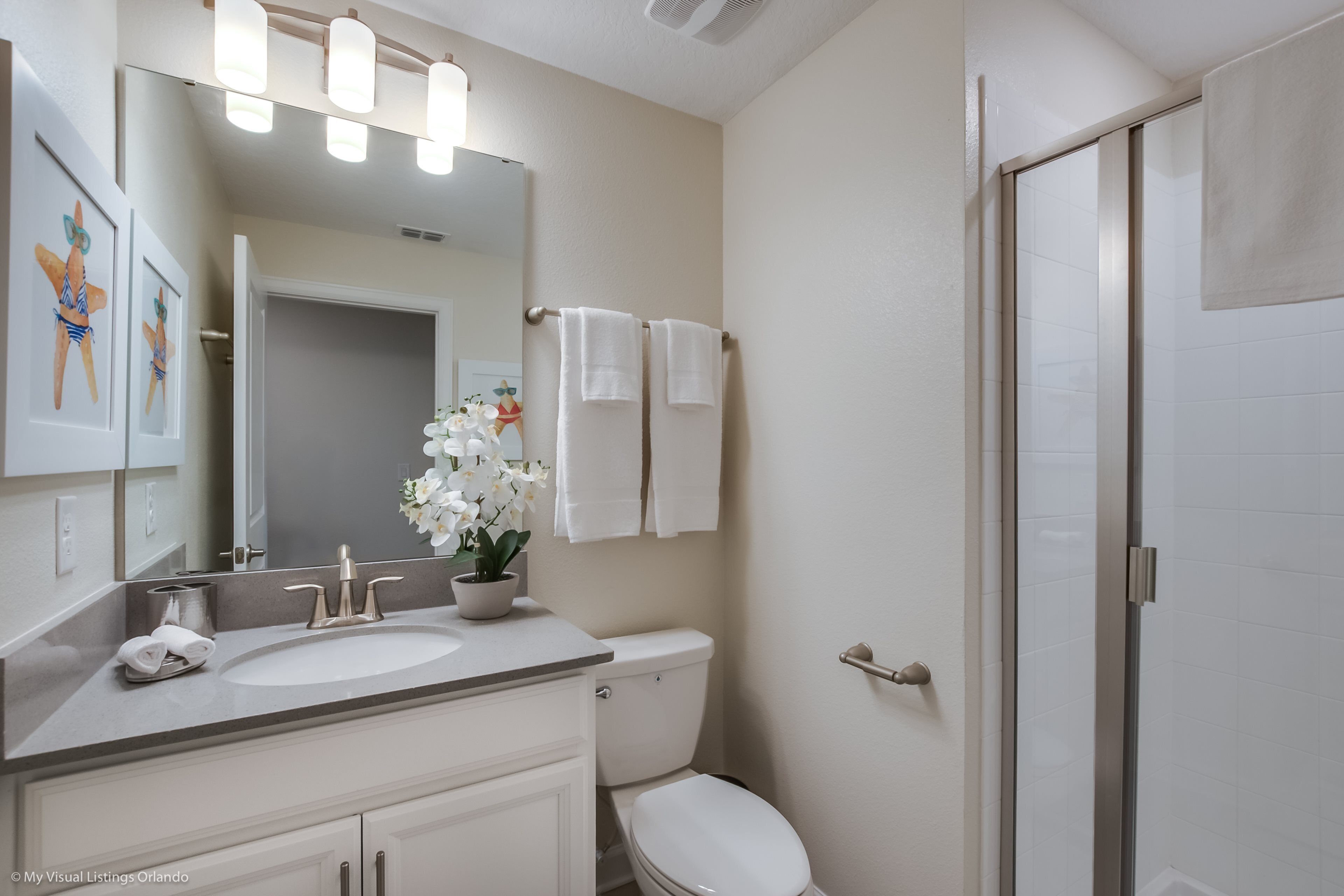 Un baño moderno con lavamanos doble, inodoro, ducha y un espejo grande.