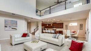 A spacious living area with a high ceiling, a dining area, and a kitchen.