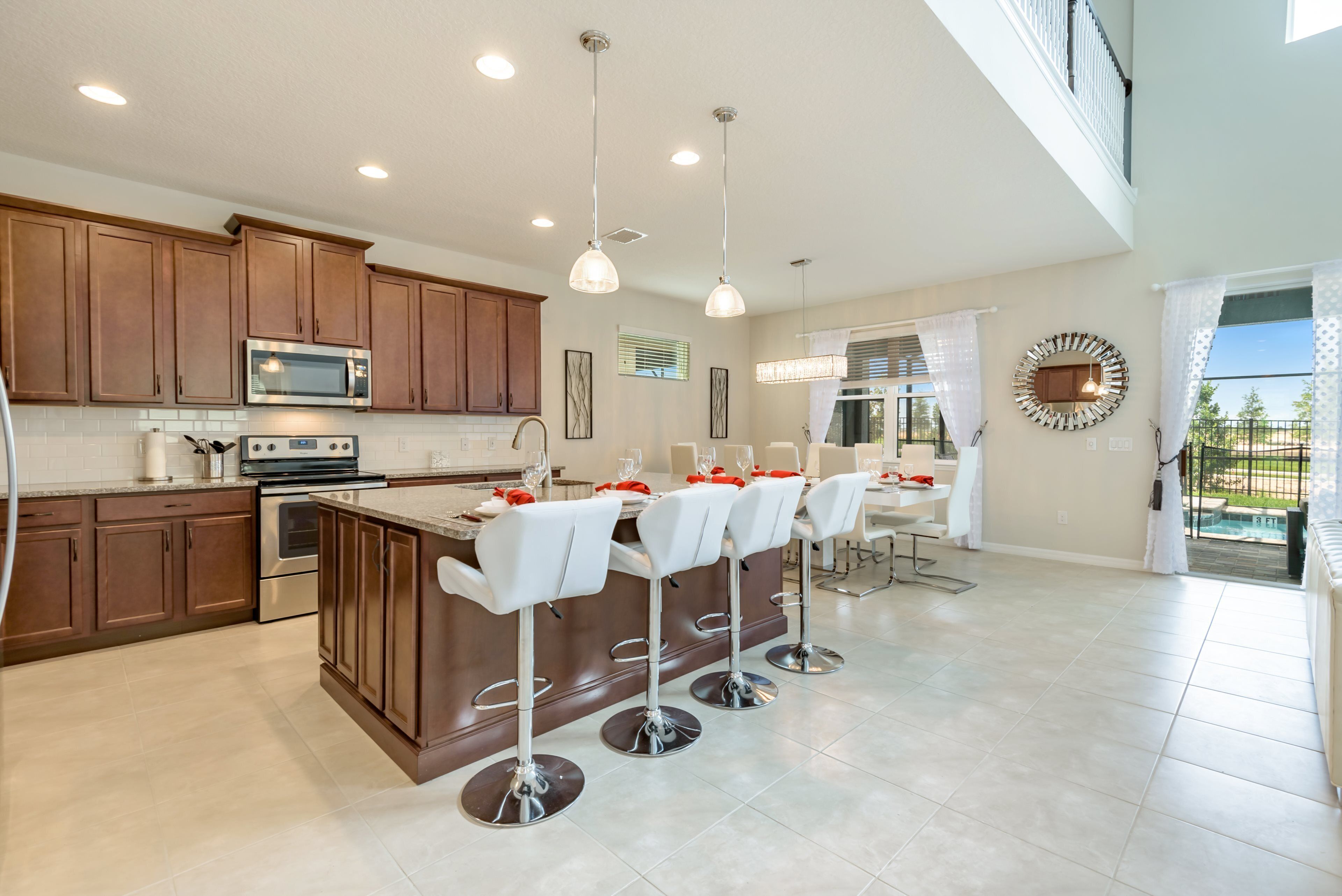 A modern kitchen with wooden cabinets, a central island with bar stools, stainless steel appliances, and pendant lighting.