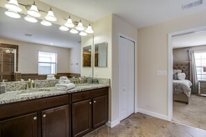 A bathroom with a large mirror, a sink with a granite countertop, and a shower area. - 7 Bdrm5ba Spa, Game Room and Theater (Davenport)
