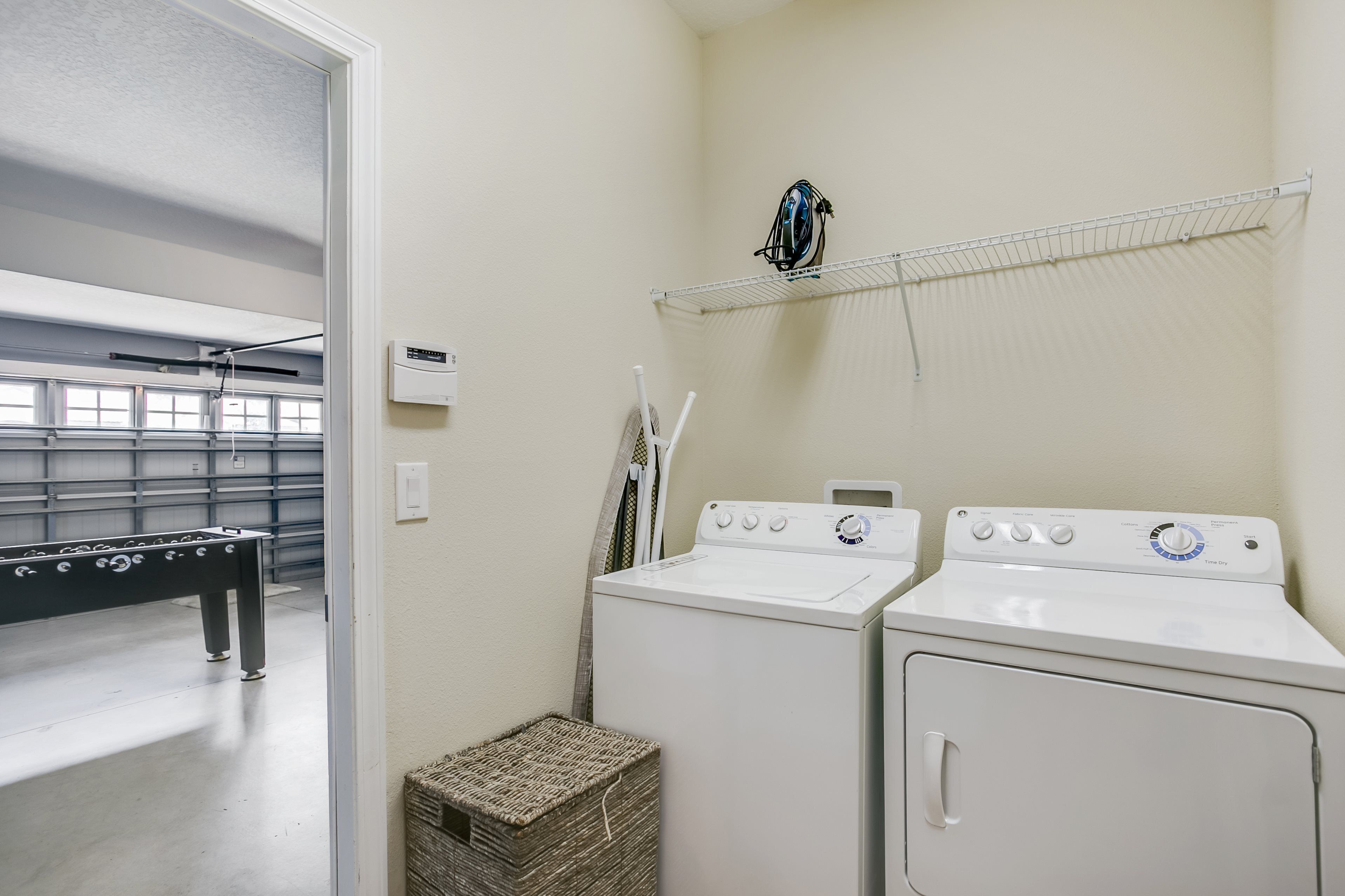 A laundry room with two washing machines, a drying rack, and a small wicker basket.
