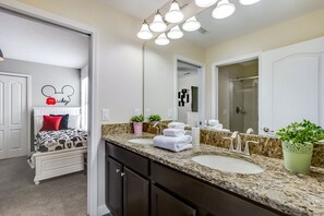 A modern bathroom with two sinks, a large mirror, and a Mickey Mouse wall decal. - 7 Bdrm5ba Spa, Game Room and Theater (Davenport)