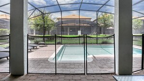 Un espace extérieur abrité comprenant une piscine, des chaises longues et une vue sur un bâtiment doté d’un toit en tuiles.