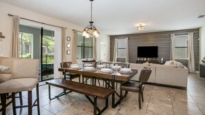 Un vaste espace de vie comprenant une table à manger pour six personnes, un canapé et un téléviseur à écran plat.