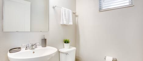 A bathroom with a white sink, toilet, and a towel rack.