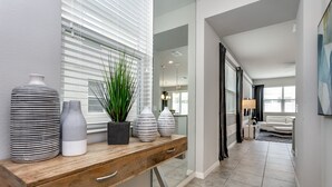 Un intérieur moderne agrémenté d’une console en bois, de vases décoratifs et d’une plante en pot.