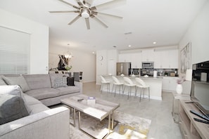 A modern living room with a grey sofa, a coffee table, and a ceiling fan.