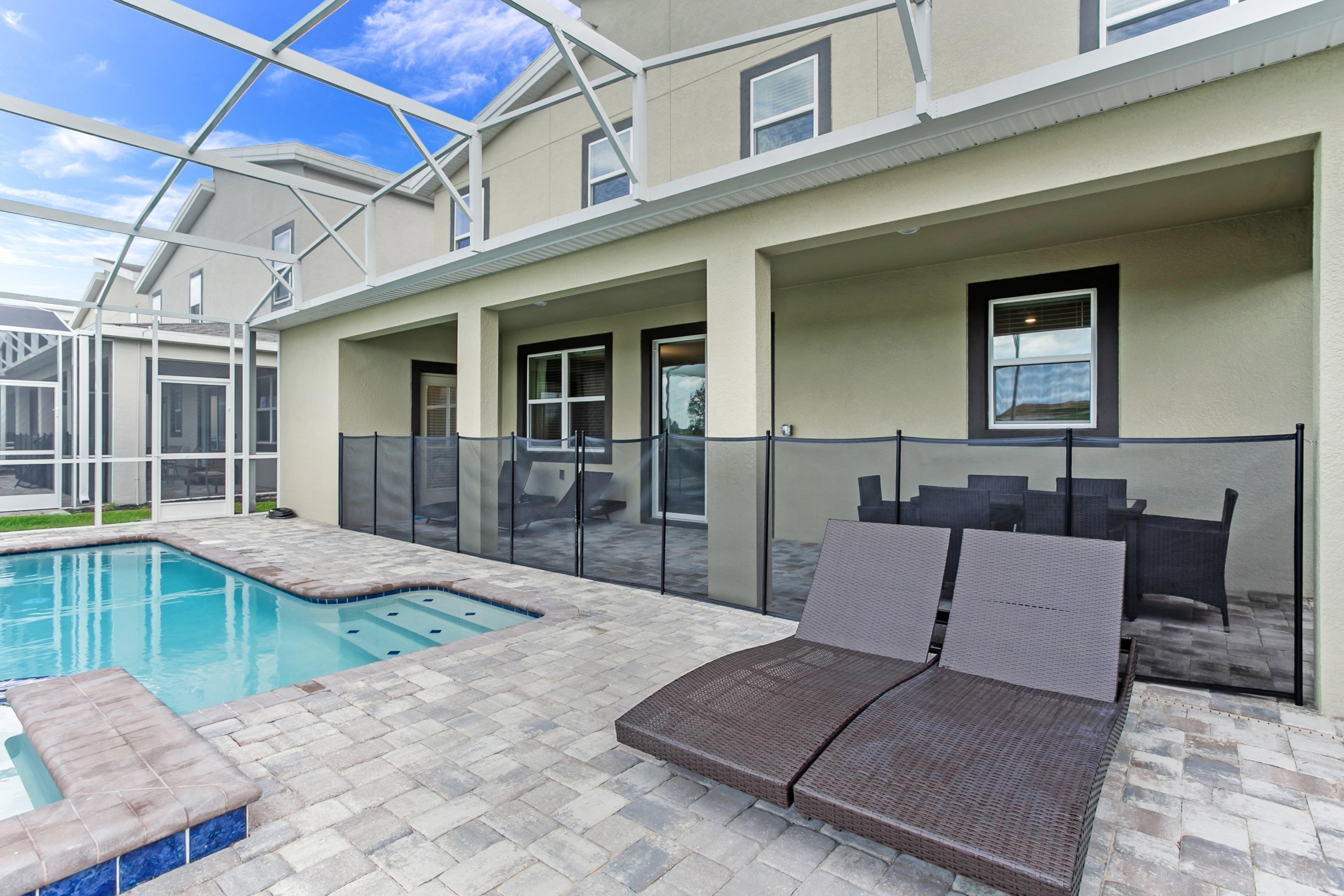 A pool area with lounge chairs, a hot tub, and a covered patio.