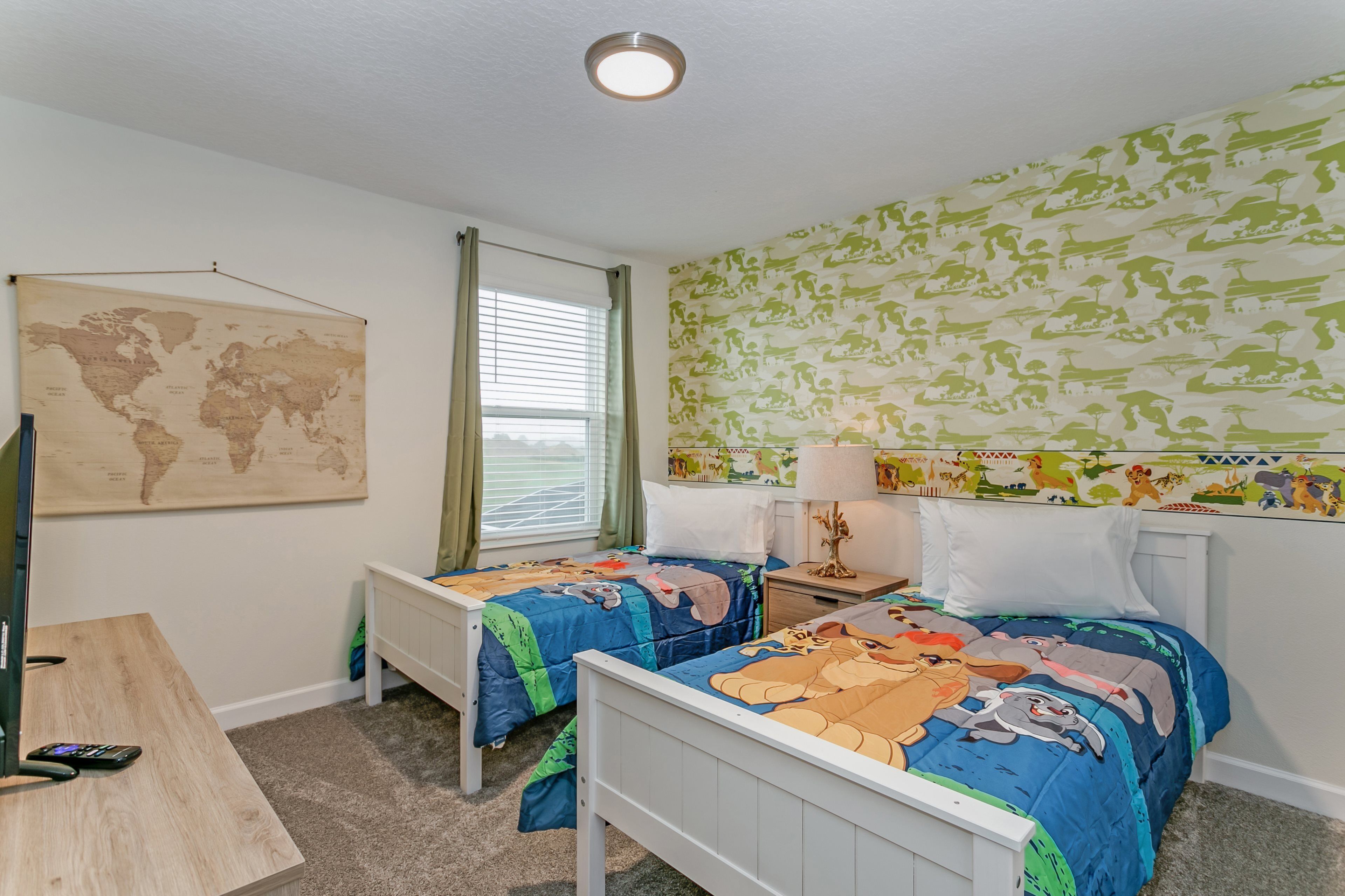 A bedroom with two beds, a world map on the wall, and a window with curtains.