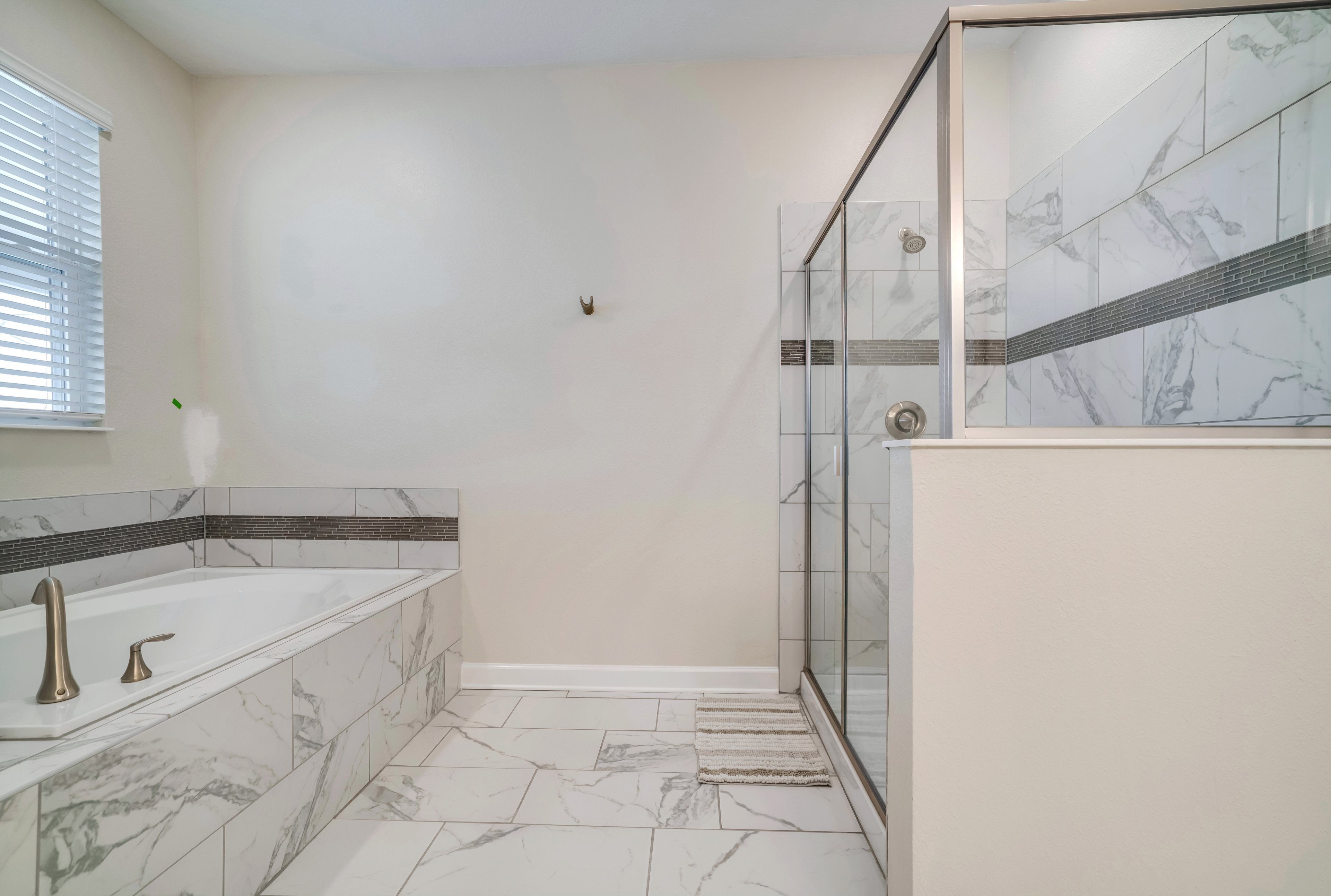 Une salle de bain équipée d’une baignoire, d’une douche et d’un espace de douche séparé par des parois en verre.