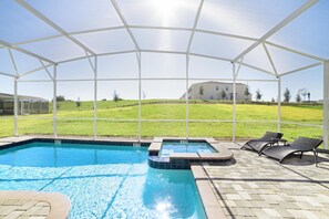 A covered outdoor swimming pool with lounge chairs and a hot tub, surrounded by a white canopy.
