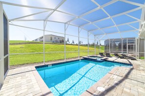Une piscine extérieure couverte offrant une vue dégagée sur une zone verdoyante et des bâtiments en arrière-plan.