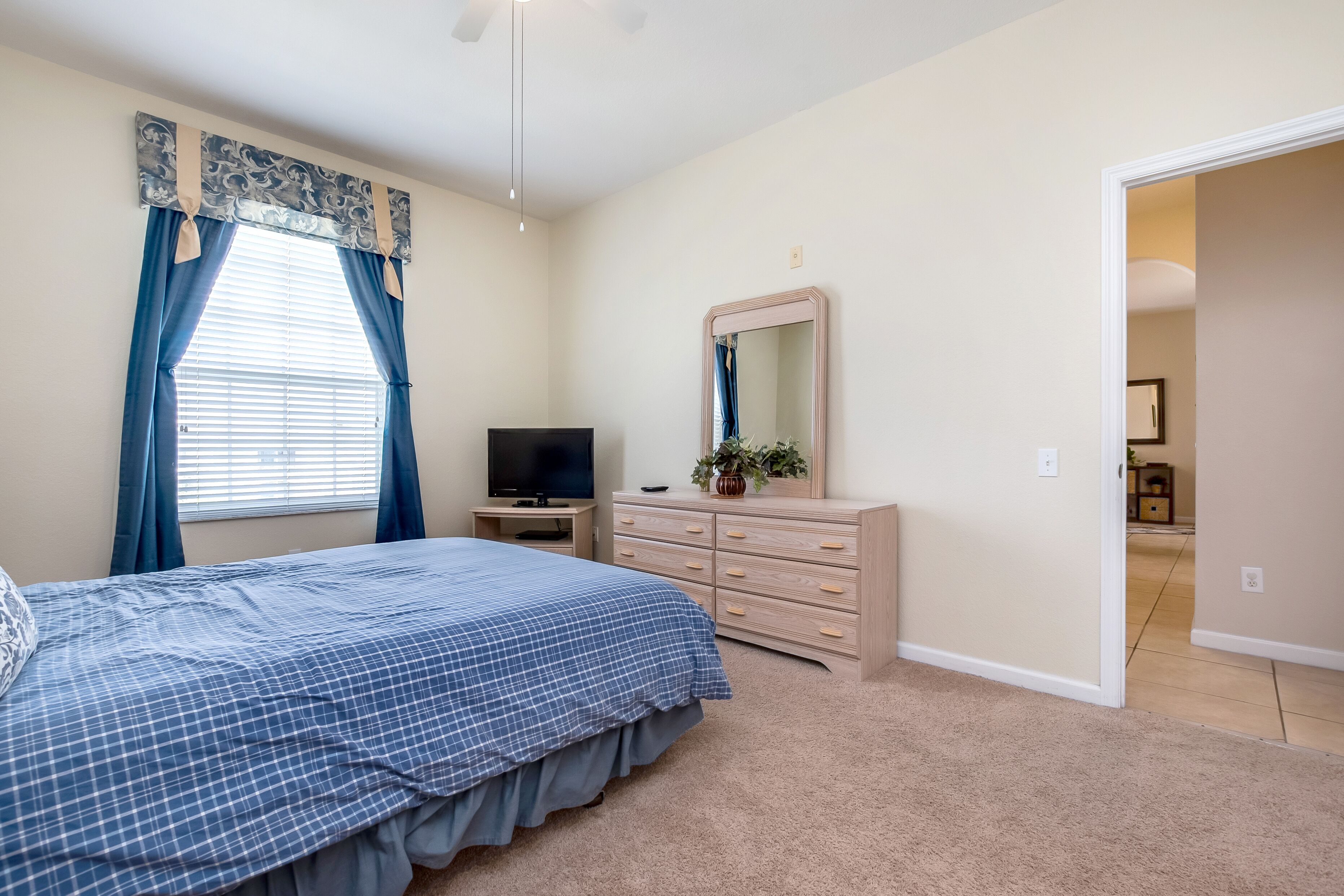Een slaapkamer met een bed, een dressoir, een televisie en een spiegel.